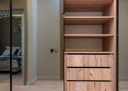 Free Interior of light apartment with wooden cabinet with empty shelves next to bed Stock Photo