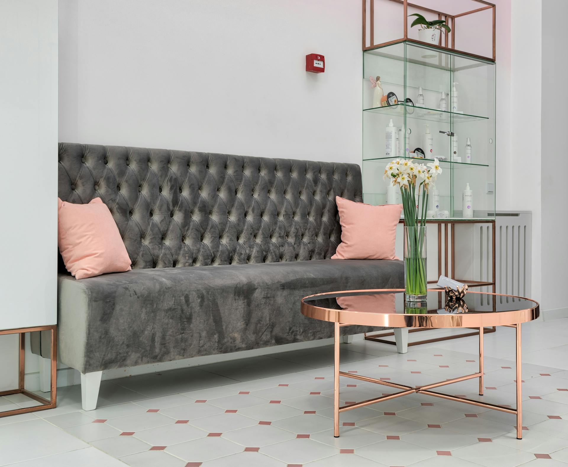 Modern lounge interior with couch against table and glass cabinet with assorted bottles on shelves