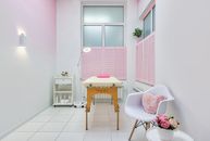 Creative design of massage salon with table between beauty products and armchair against blossoming peonies in pot