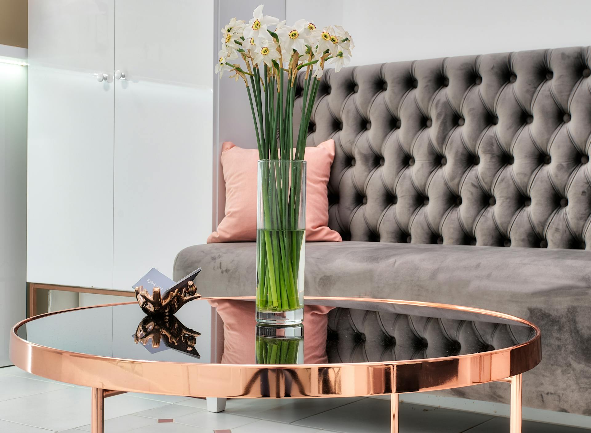 Blooming Narcissus bouquet in vase against couch in modern lobby