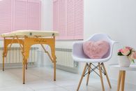 Creative design of massage parlor with table and decorative heart shaped cushion in armchair on tiled floor