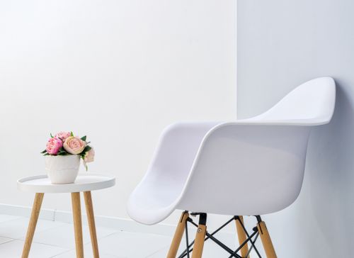 Free White armchair against small table with blossoming flowers in pot in contemporary lounge with tiled floor Stock Photo