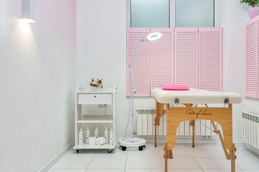 Interior of modern beauty salon with assorted skin products and couch for clients placed against window covered with shutters