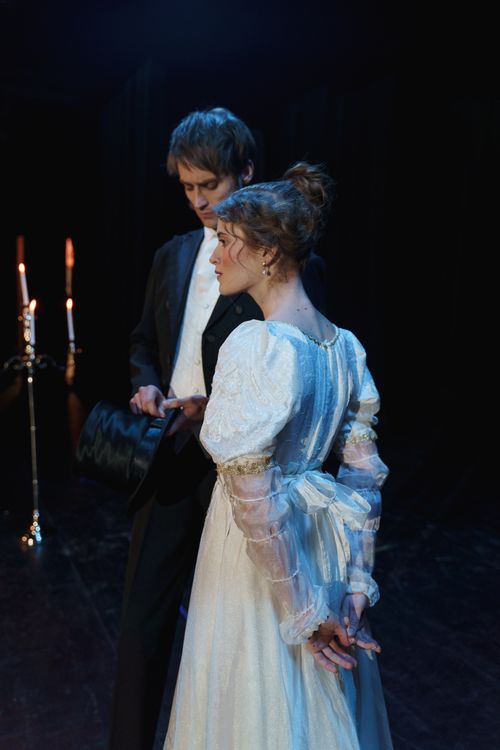Free Victorian-era couple performing a dramatic scene in theater with candlelight. Stock Photo