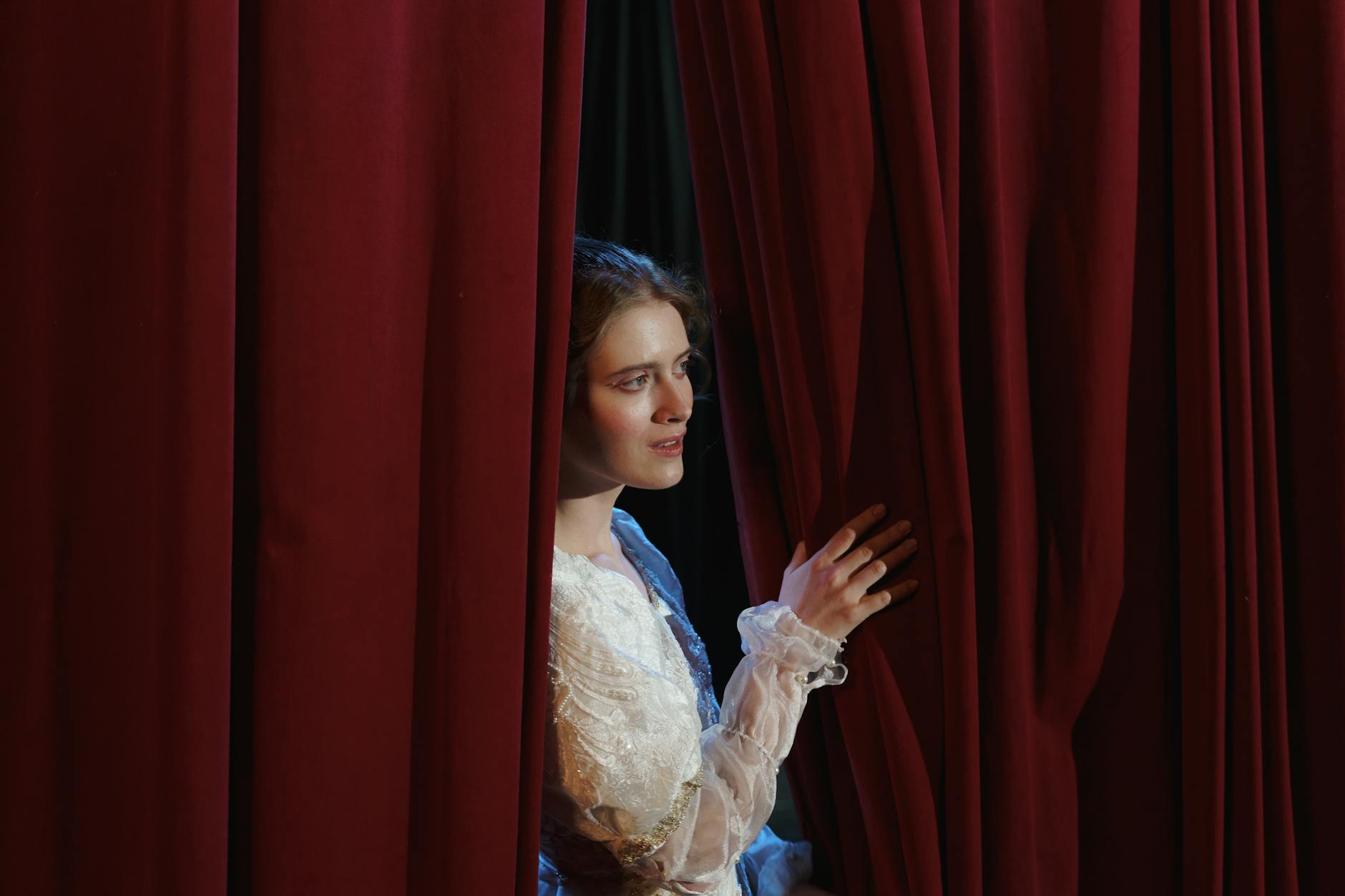 Woman in White Floral Lace Dress Standing Behind a Curtain