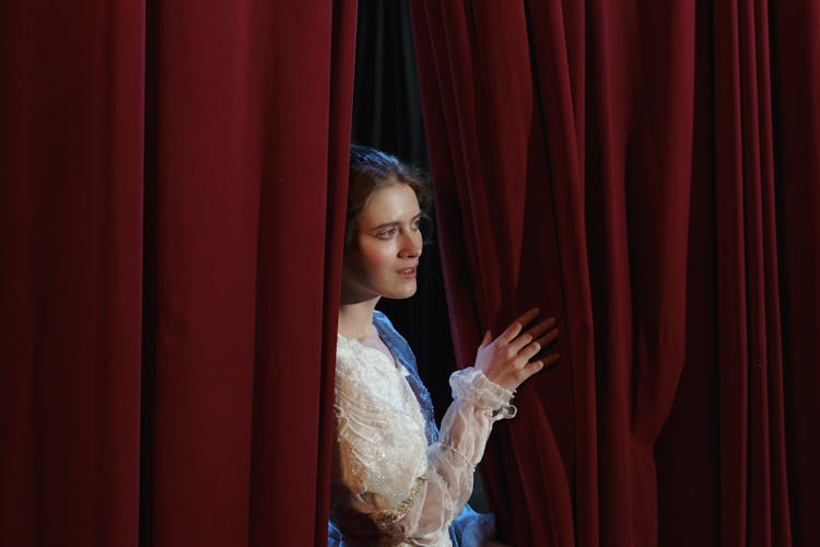 Woman In White Floral Lace Dress Standing Behind A Curtain