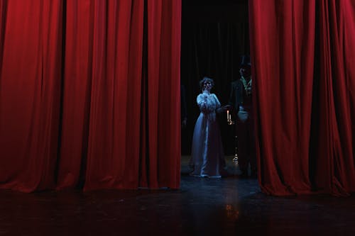 Man And Woman Standing Behind A Red Curtain