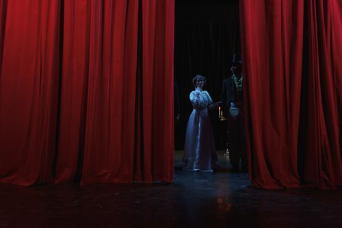 Free Dramatic stage scene with actors behind red curtains, creating a theatrical ambiance. Stock Photo