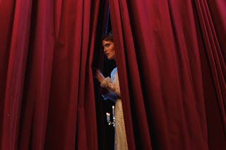 Woman Standing Behind Red Curtain