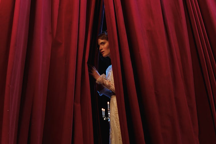 Woman Standing Behind Red Curtain