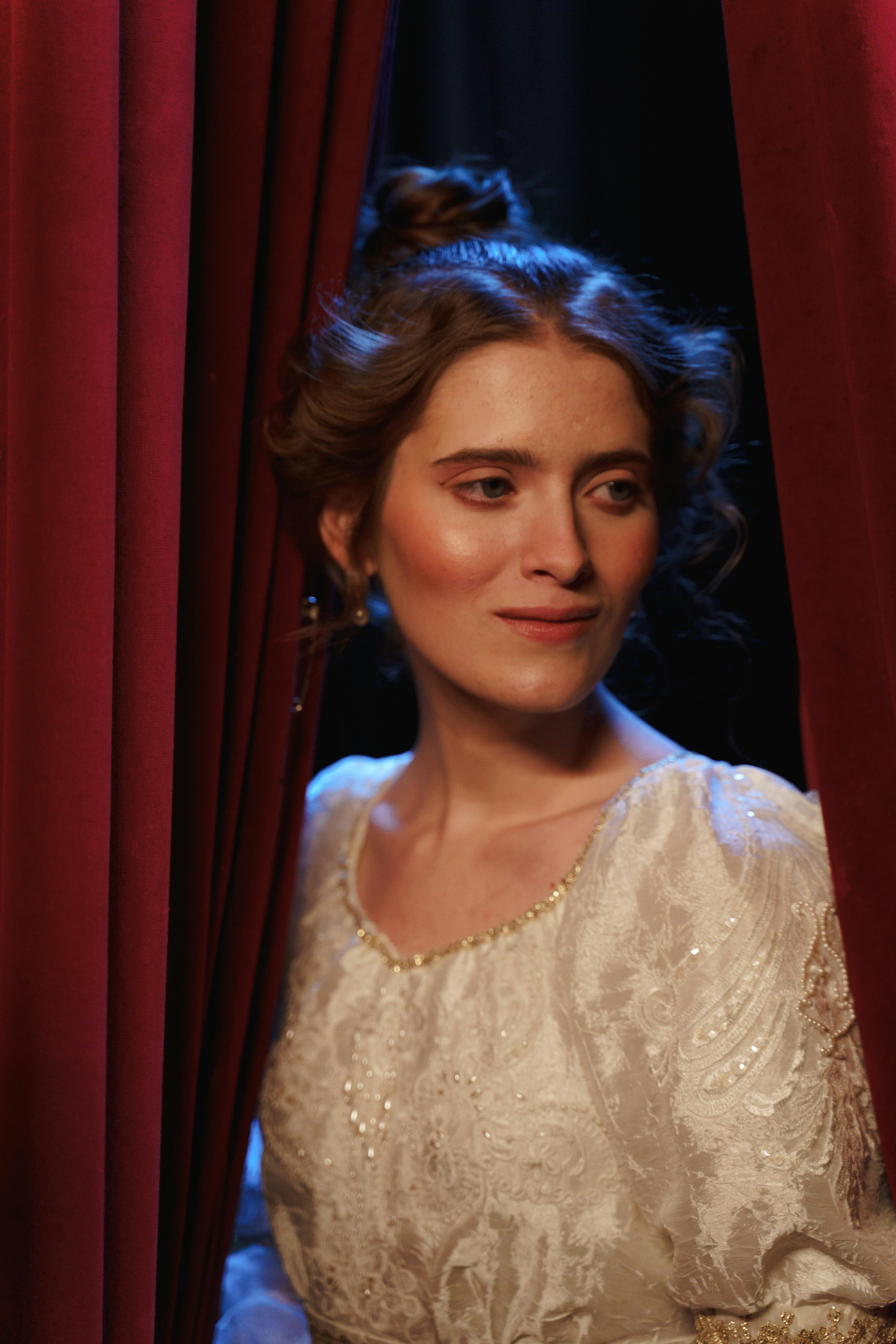 woman in white lace dress behind a curtain