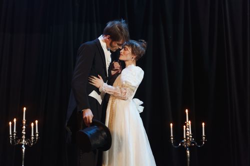 Free A dramatic romantic scene on stage with a couple in classic costumes surrounded by candlelight. Stock Photo