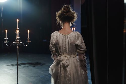 Free A woman in a white dress stands backstage under dramatic lighting, evoking a classic theatrical ambiance. Stock Photo