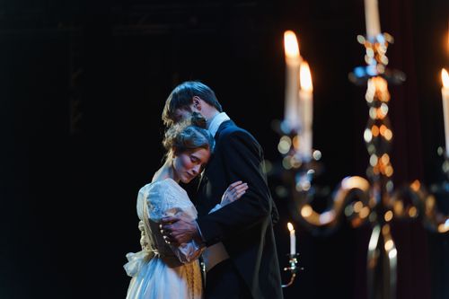 Free A romantic embrace on stage between actors in elegant costumes under warm lighting. Stock Photo