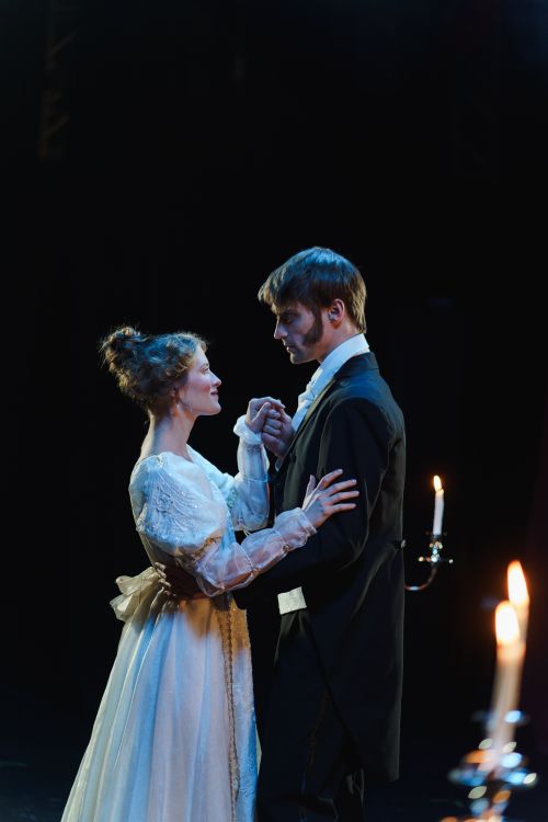 Free A romantic theater scene with a couple performing in elegant costumes by candlelight. Stock Photo
