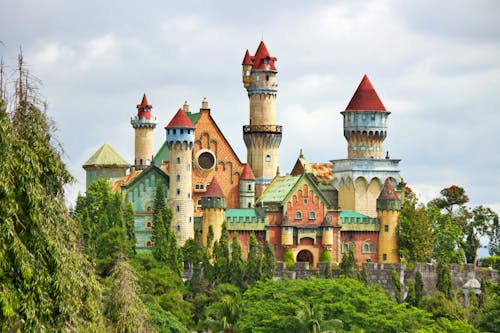 A Castle Surrounded by Green Trees Under White Clouds