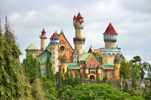 Free A vibrant fairytale castle surrounded by lush greenery and dramatic clouds in Lemery, Philippines. Stock Photo