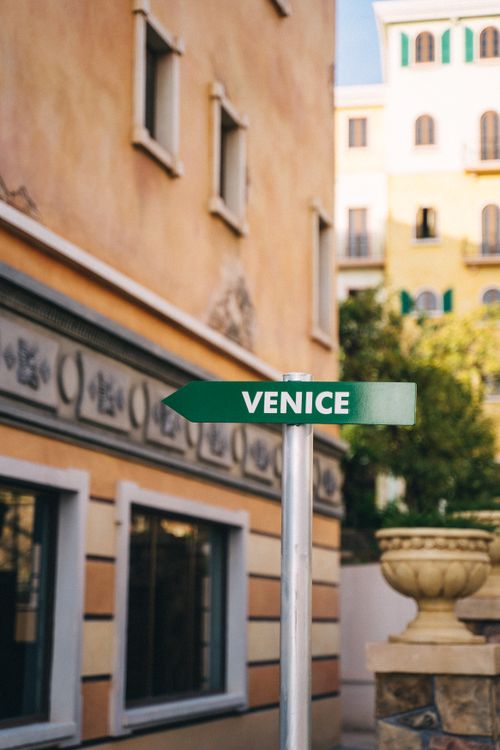 Free Green direction sign pointing to Venice in an urban cityscape. Stock Photo