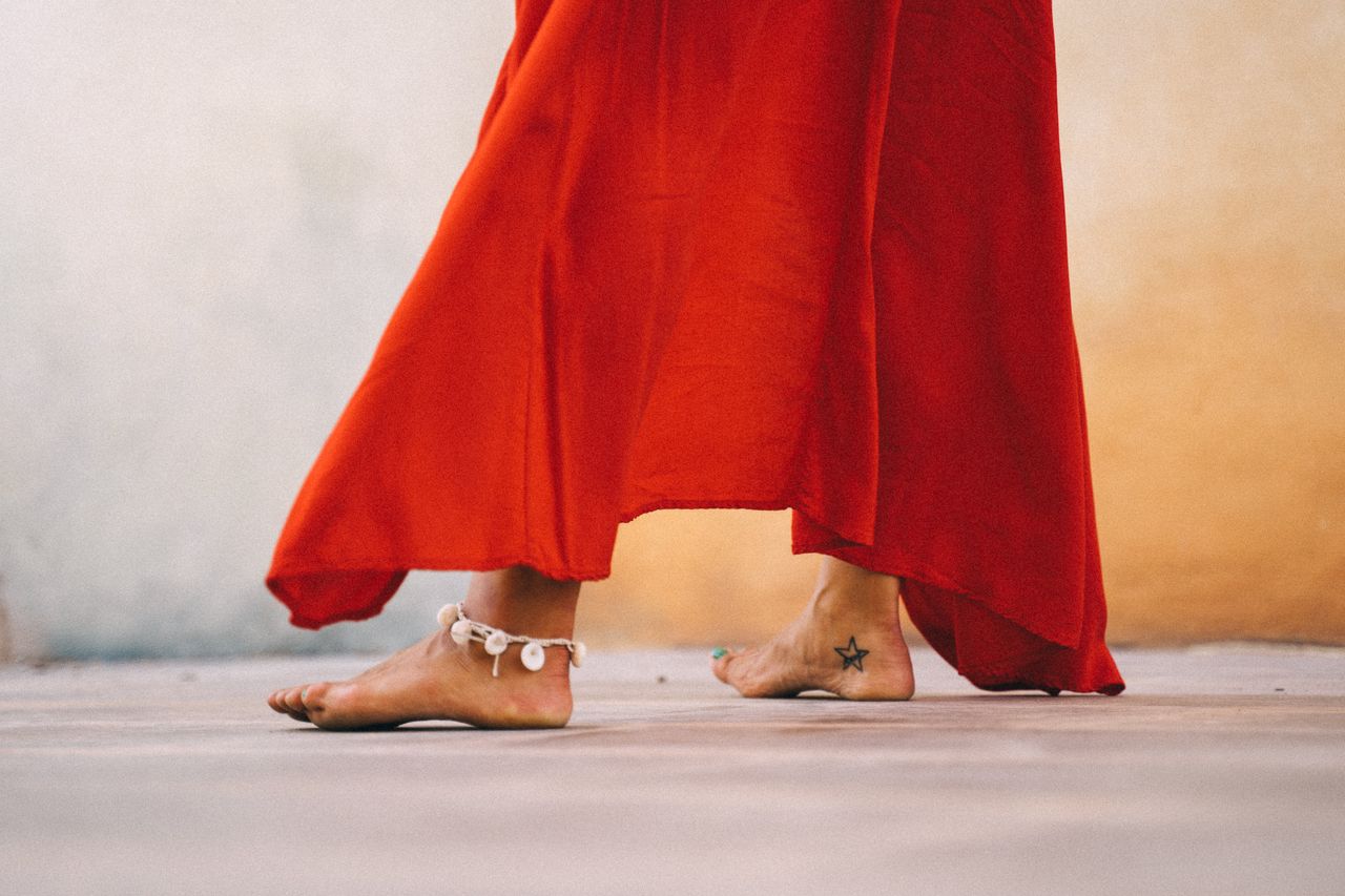 close up of a woman dancing barefoot in a flowing red dress with ankle