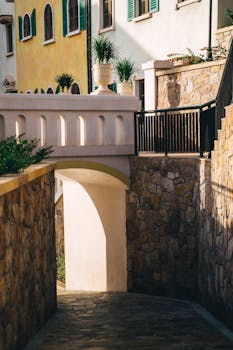 A picturesque Italian-style street with vibrant facades, archway, and lush greenery.