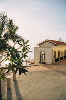 Charming Mediterranean villa by the sea with palm trees at sunset, exuding serenity and elegance.