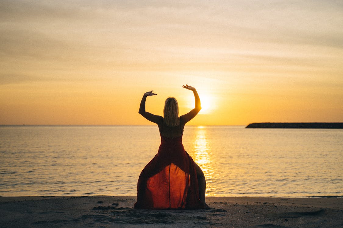 Woman in Orange Dress Standing on Beach during Sunset