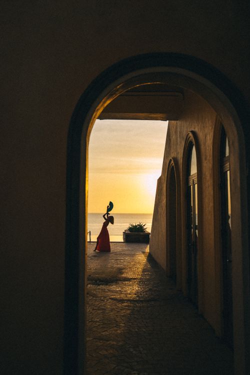 Free Captivating silhouette of a dancer in a red dress holding a fan during a golden sunset. Stock Photo