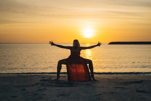 A graceful dancer silhouetted against a stunning sunset on the beach, wearing a flowing red dress.