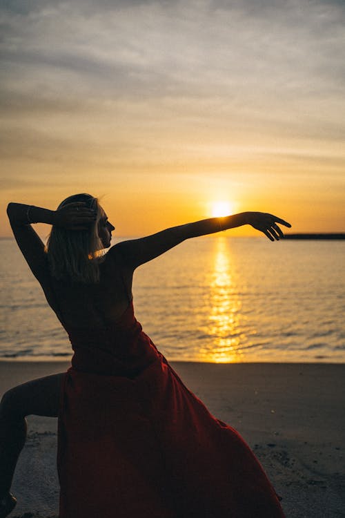 Woman in Red Dress Standing on Beach Shore