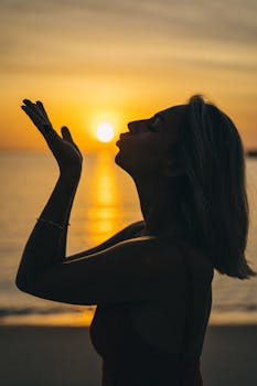 Silhouette of a woman kissing the golden sunlight at the beach during sunset in Vietnam.