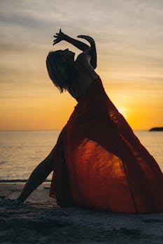 Captivating silhouette of a woman in a red dress dancing on a Vietnamese beach at sunset.