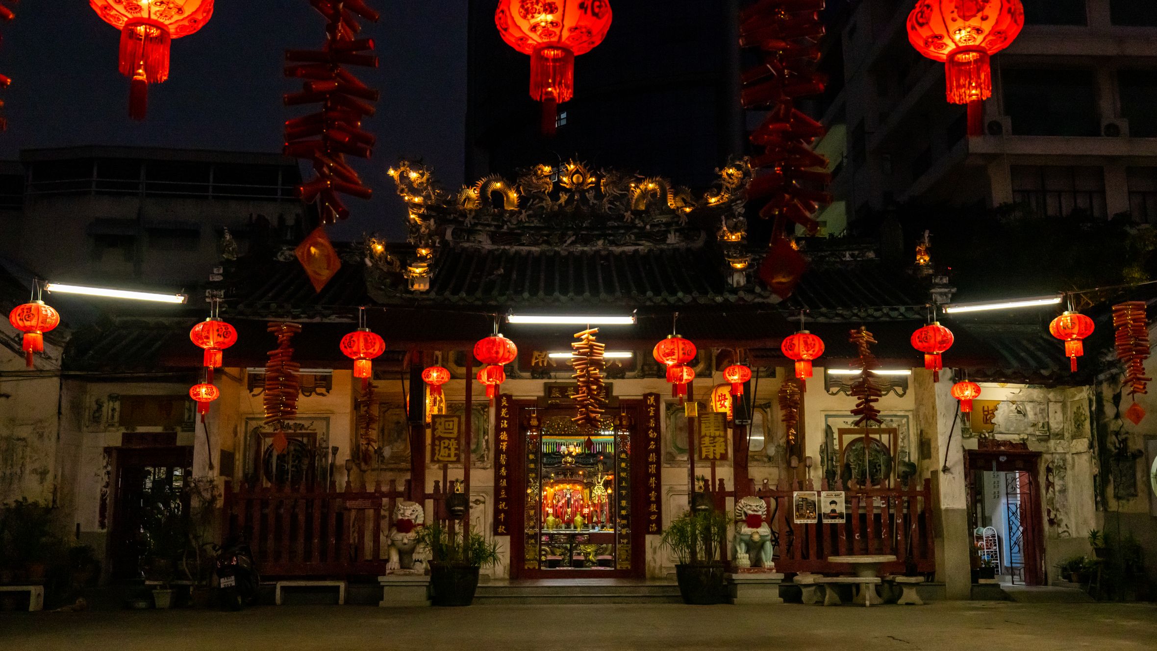 Temple entrance illuminated by red lanterns for a festive celebration at night.