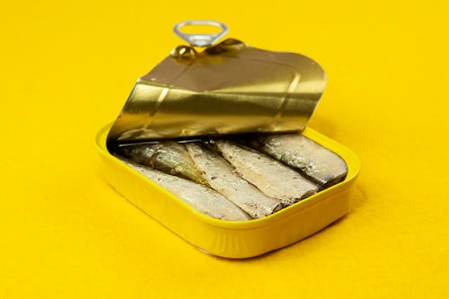 Gratis lagerfoto af dåse af sardiner, gul overflade, plads til reklametekst
