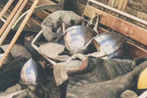 Two Gray Stainless Steel Soldier Helmet on Brown Wooden Bench