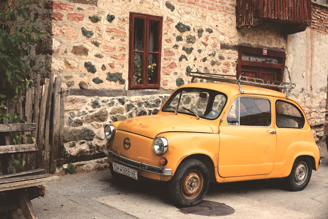 żółty Nissan Classic Car Obok Budynku Z Betonu Szaro Beżowego