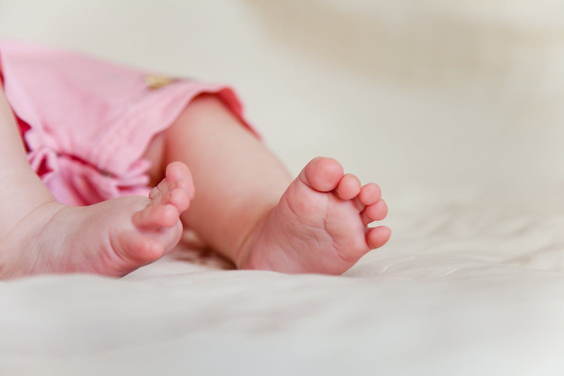 Free Close-Up Photo of a Baby's Feet on a White Surface Stock Photo