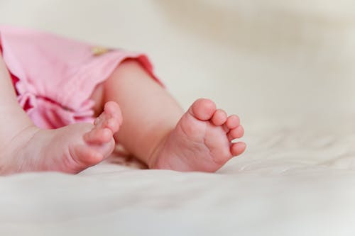 Close-Up Photo of a Baby's Feet on a White Surface