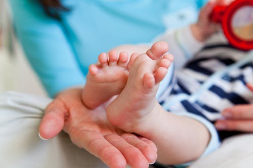 Infant Feet on Person's Hand 