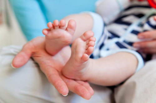 Free A Child's Feet on a Person's Hand Stock Photo