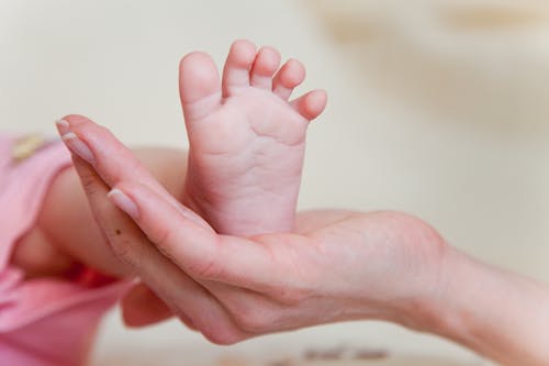 Free Close-Up Photograph of a Person's Hand with a Baby's Foot Stock Photo
