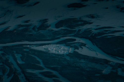 Free Drone view of frozen curvy river flowing through vast valley covered with snow Stock Photo