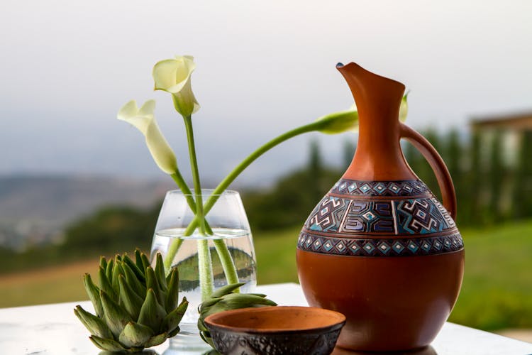 Vase With A Pattern And White Callas Standing On The Table Outside 