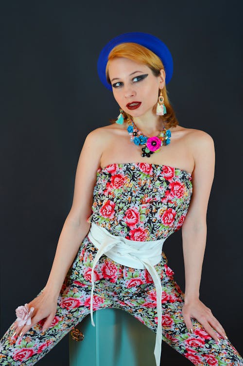 Gorgeous young woman in trendy outfit sitting in studio and looking away