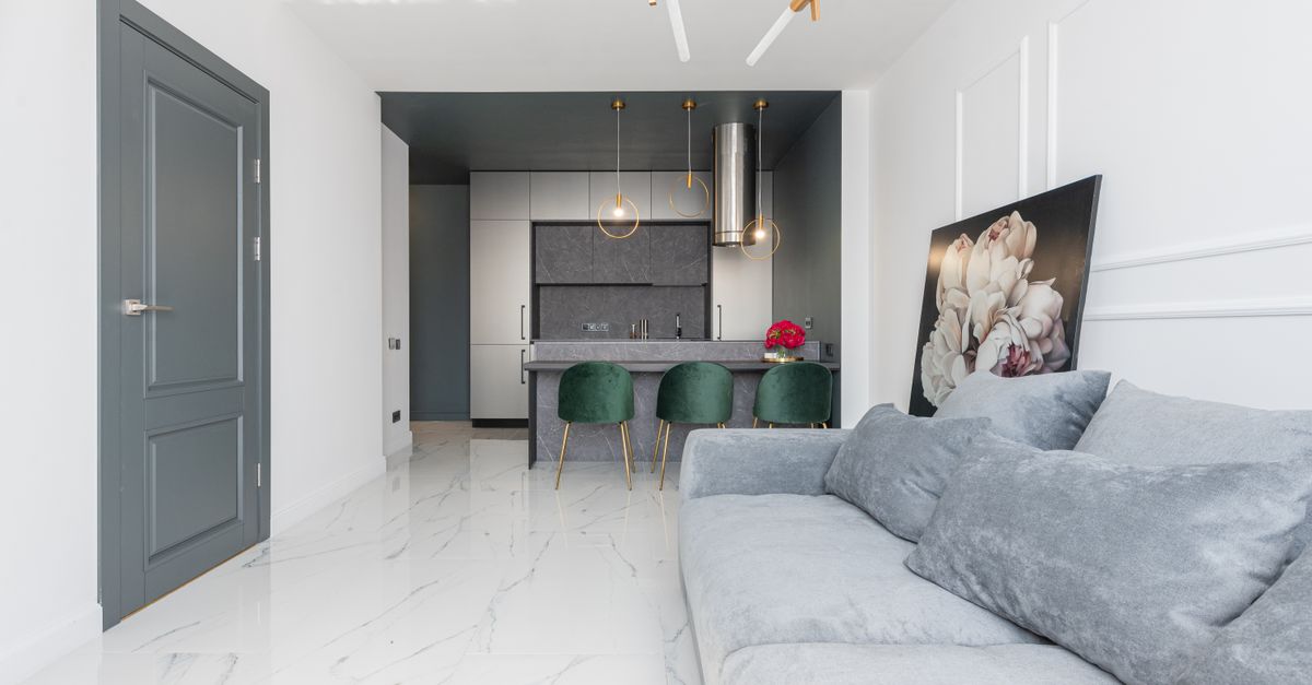 Contemporary studio apartment furnished with soft couch in living zone and armchairs and cupboards in kitchen
