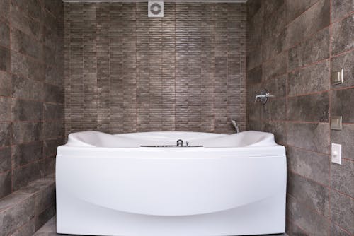 Modern bathtub in bathroom with tiled walls