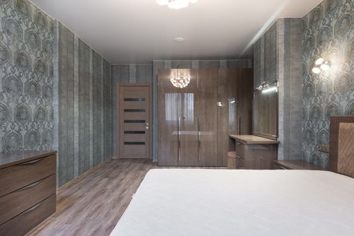 Free Spacious room with bed and glossy cupboard with wooden dressers under light of chandelier Stock Photo