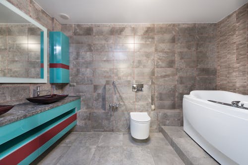 Interior of contemporary bathroom with modern toilet and bathtub with mirror hanging above sink