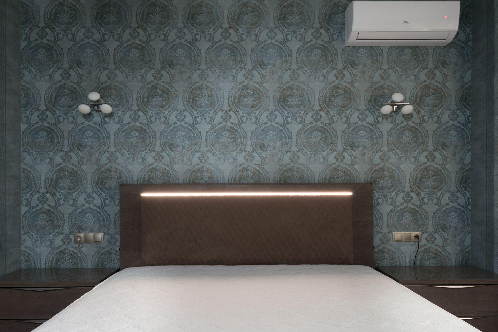 Blue patterned wallpaper behind a brown headboard and light bed with wall-mounted lamps.