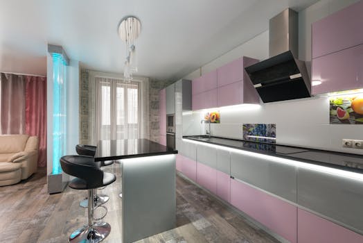 A stylish and spacious modern kitchen with pink cabinets and black countertops.