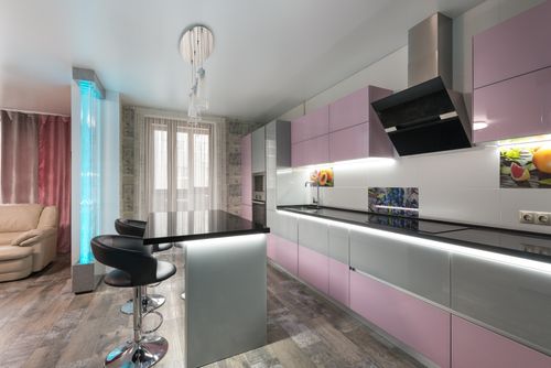 Free Table with chairs placed near colorful cupboards with modern appliances in stylish kitchen with decorative bubble wall in spacious apartment Stock Photo